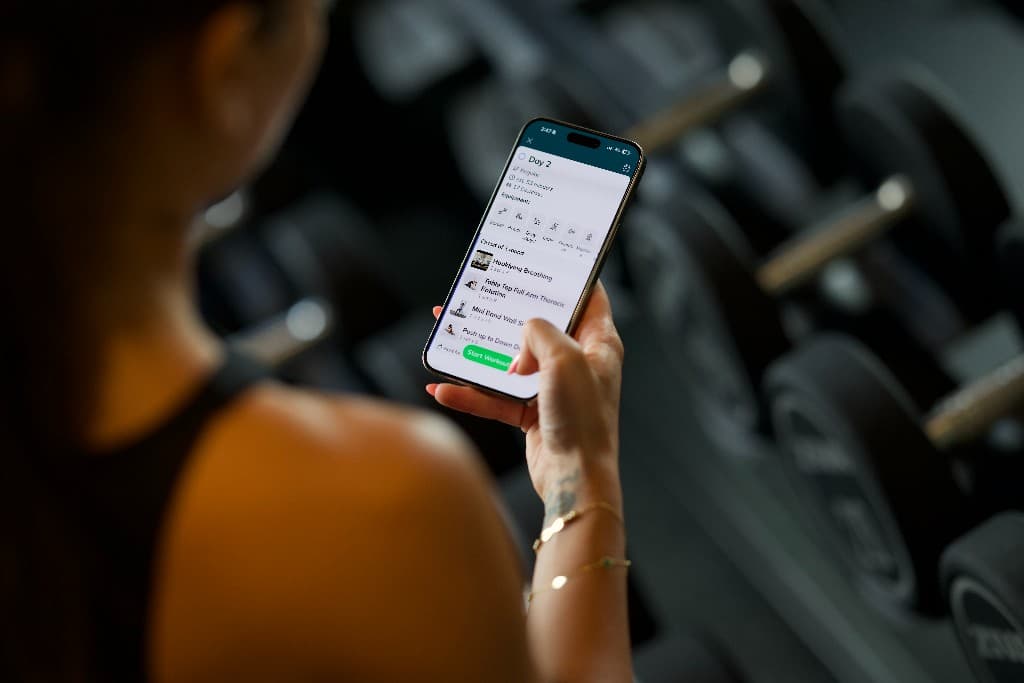 Person viewing their personalized everybody workout on a phone at the gym