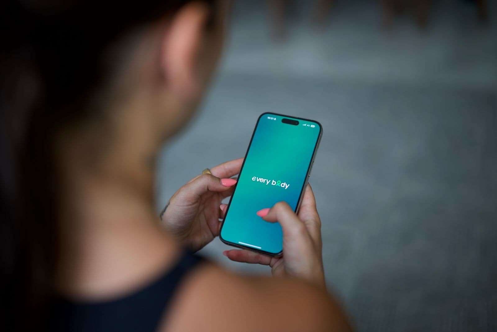 A woman opening the everybody app on her phone, representing the moment a new client begins their personalised coaching journey.