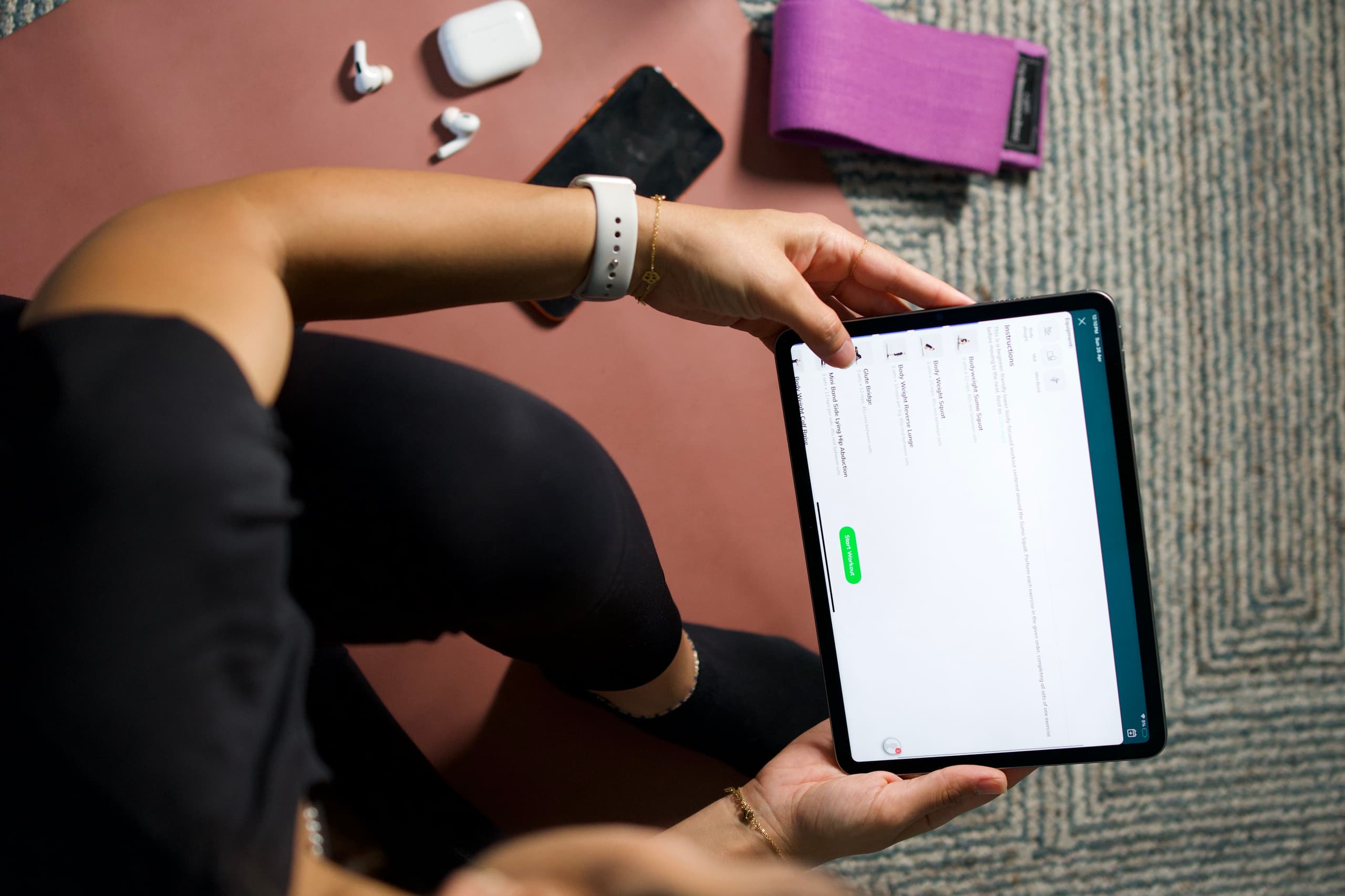 Person checking an online fitness coaching workout plan on a phone in a gym in Dubai.