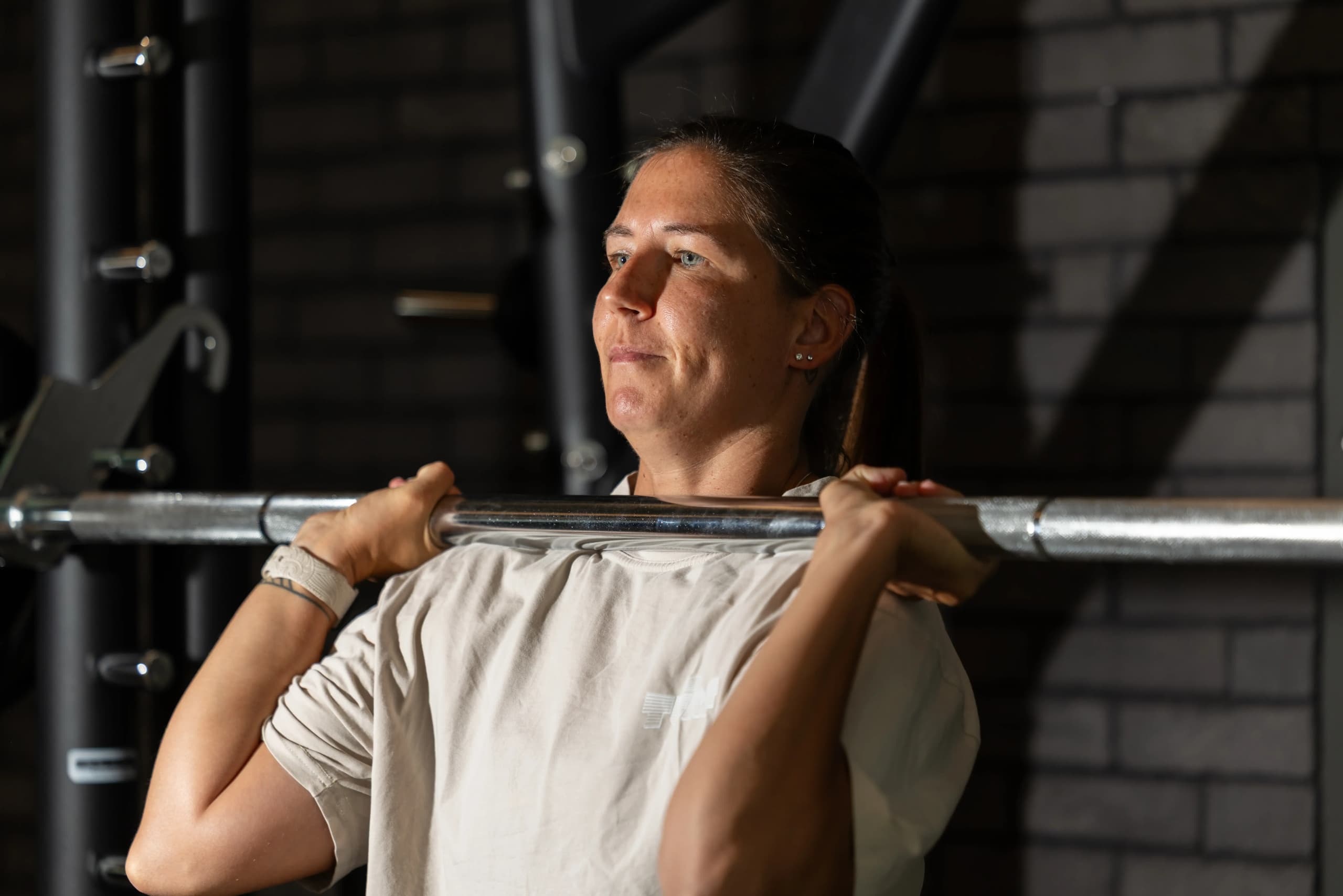 Female athlete resting between strength training sets in a gym environment