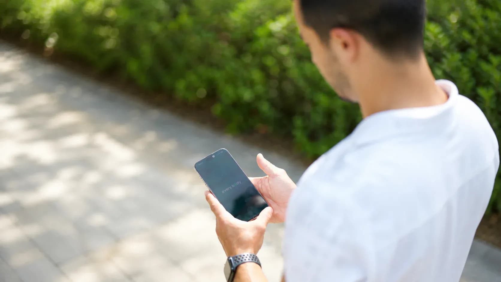 Man using a smartphone outdoors to browse and choose an online fitness coach