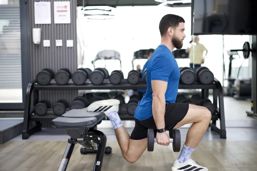 Man performing strength training lunges in a gym focused on fat loss and body composition