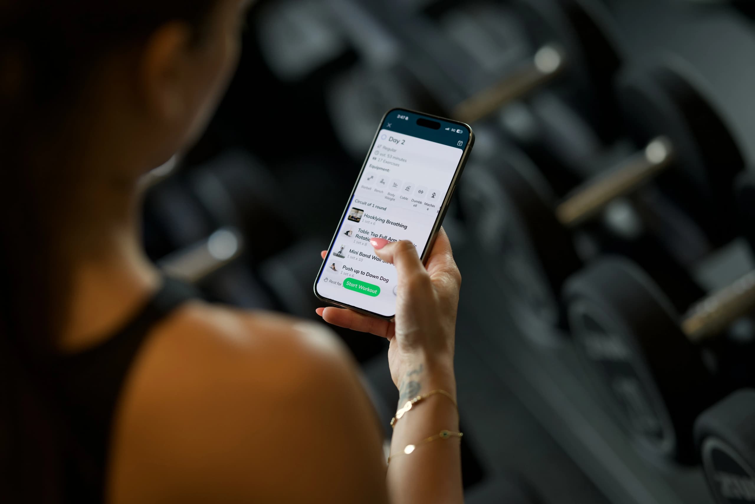 woman checking her fitness coaching app on her phone in the gym